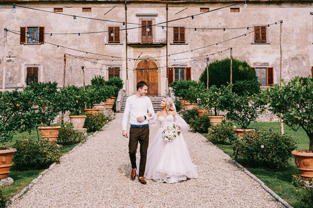 Newlyweds walking hand in hand at villa garden, Umbria wedding photographer style