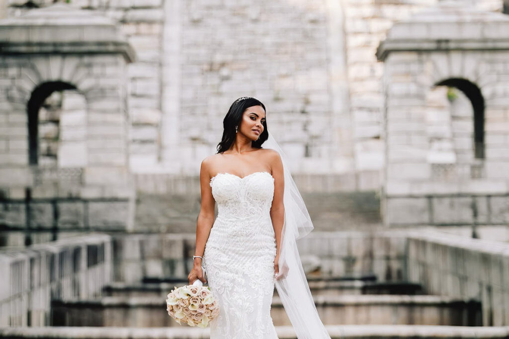Italian Wedding Photographer shows a bride in a white dress against a stone building in Umbria, highlighting the region's rustic charm