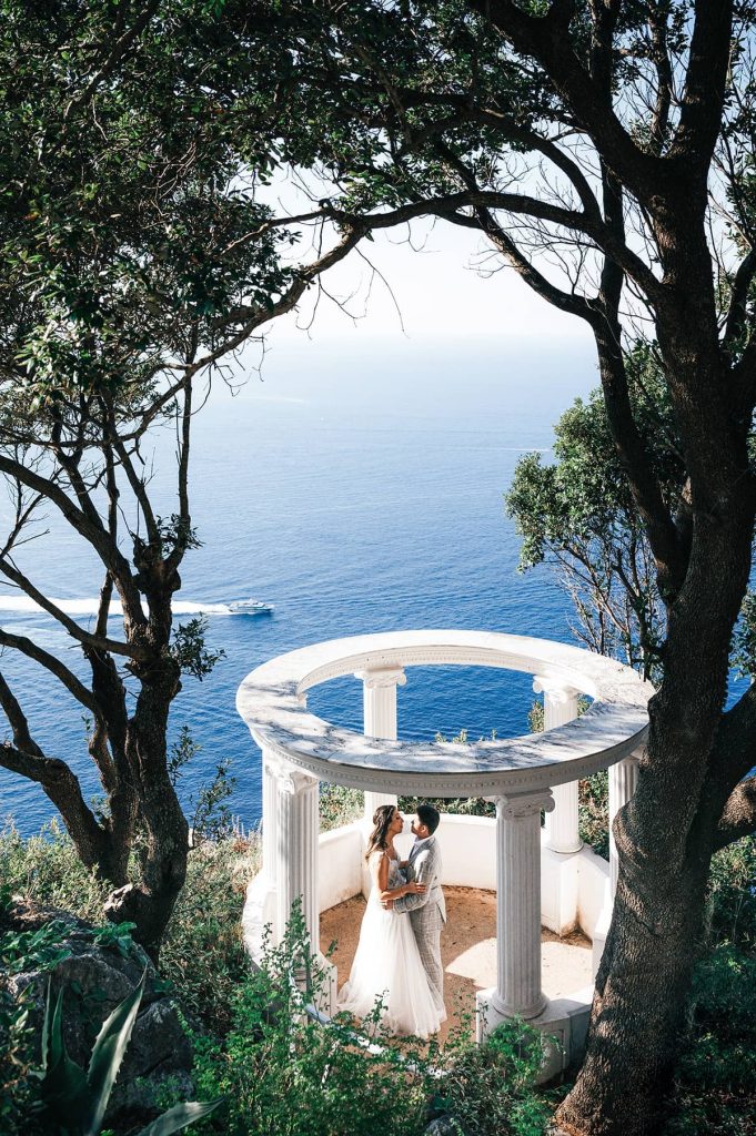 A romantic newlywed moment captured by a Capri wedding photographer in a scenic temple overlooking the sea