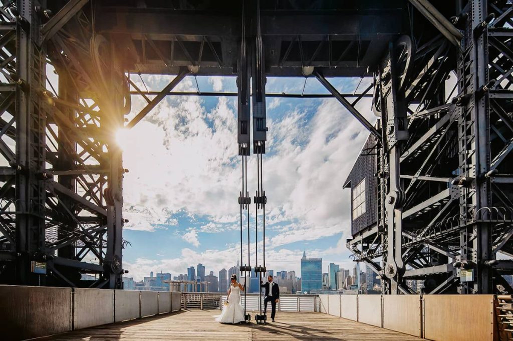 Italian Wedding Photographer shows a couple walking under a metal structure in New York City, highlighting the contrast with Italian weddings