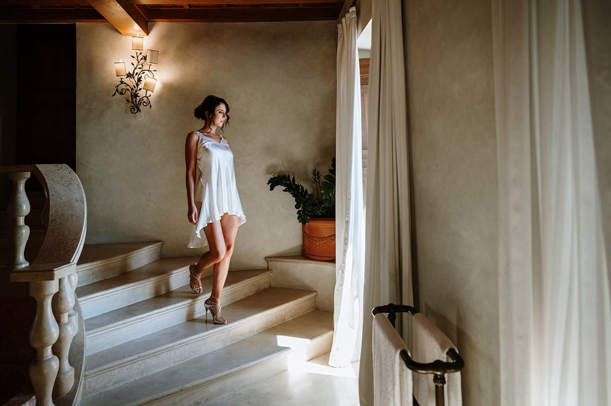 Bride in a short dress descending an elegant staircase with soft lighting