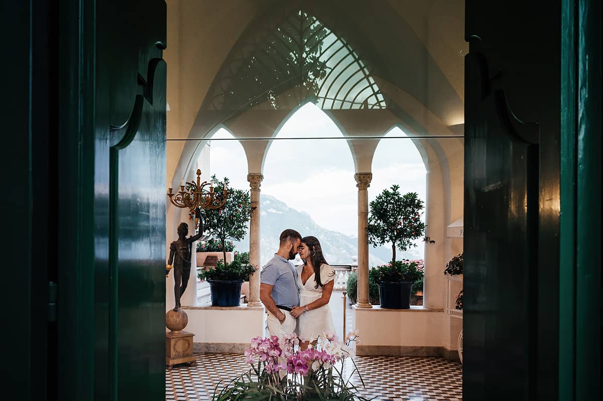 Couple at Italian Villa Affectionate couple in light blue and white attire inside a picturesque Italian villa with arched windows overlooking mountains