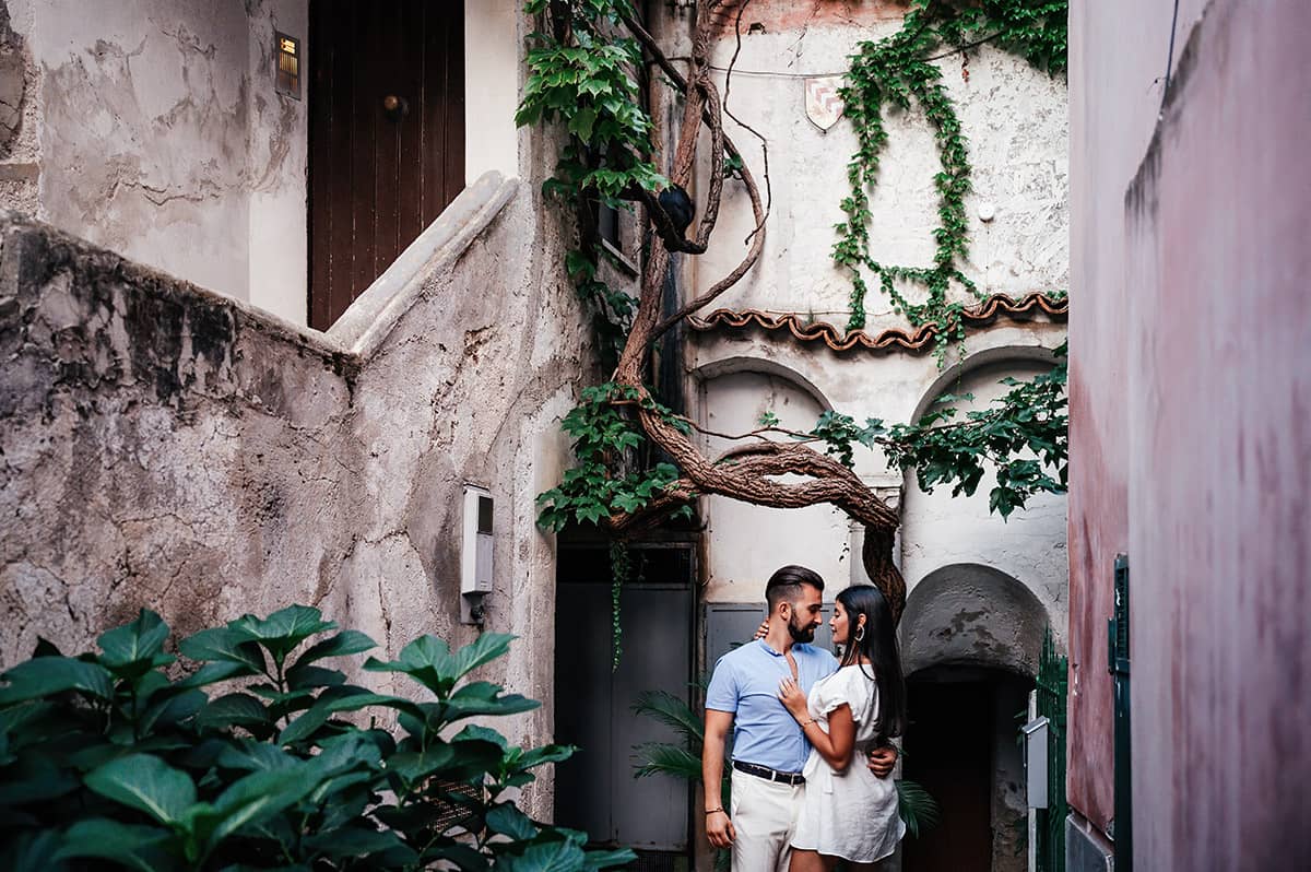 Romantic Embrace in Ravello A couple embraces in a charming alleyway with stone walls and lush greenery in Ravello, Italy.