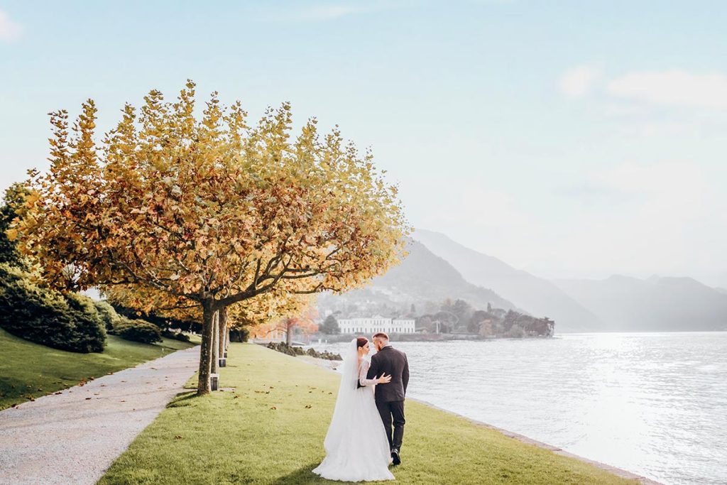 Italian Wedding Photographer captures a couple with Lake Como and a golden tree, showcasing the scenic beauty of the region