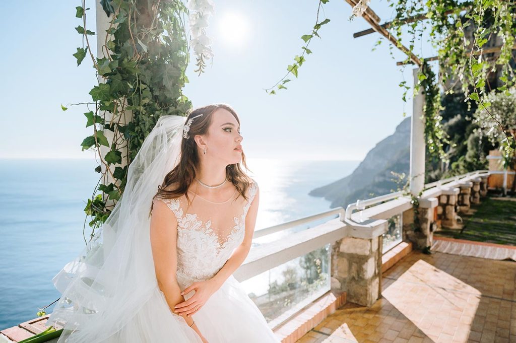 Bride in a white gown on a scenic Capri balcony, showcasing the stunning location and the expertise of a Capri wedding planner
