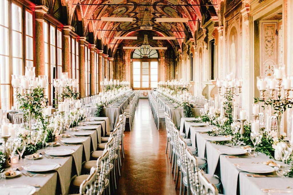 Luxurious wedding reception in a historic Tuscan villa, featuring long banquet tables elegantly decorated with candles and greenery, planned by a Tuscany wedding planner