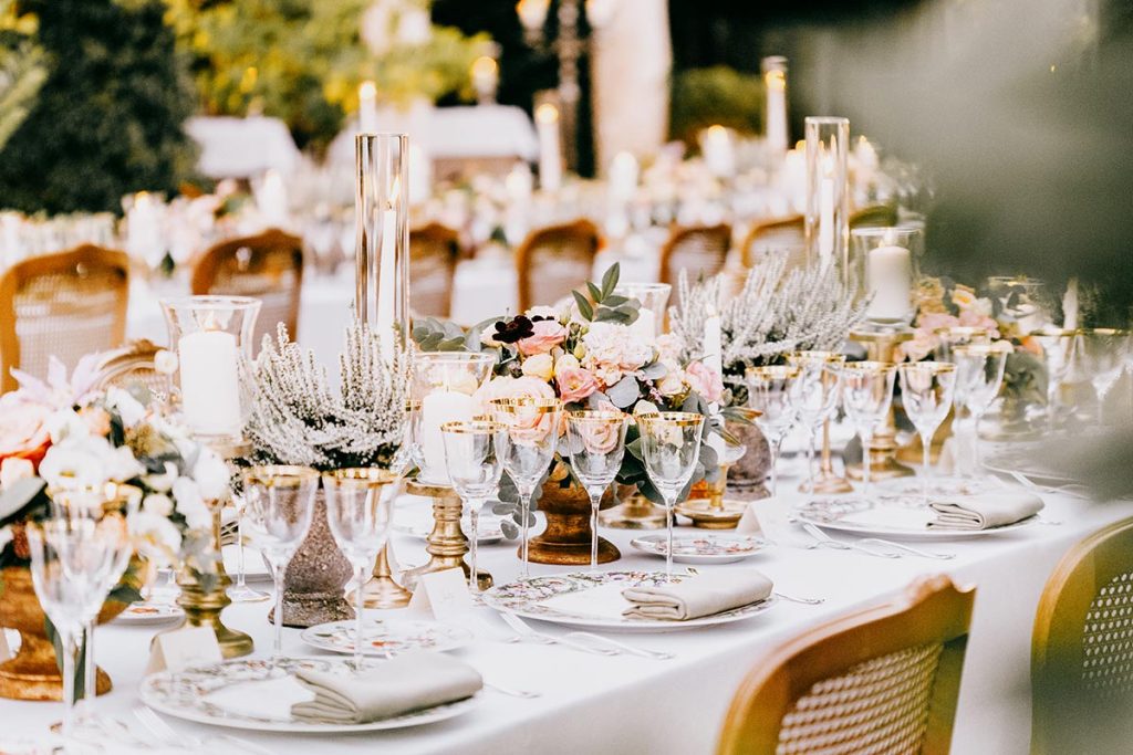Close-up of a beautifully set wedding table with floral arrangements and crystal glassware, organized by a Tuscany wedding planner