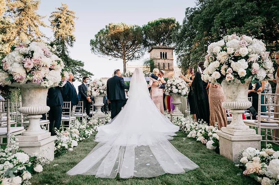 Bride walking down the aisle in a stunning outdoor wedding in Rome, surrounded by elegant floral arrangements