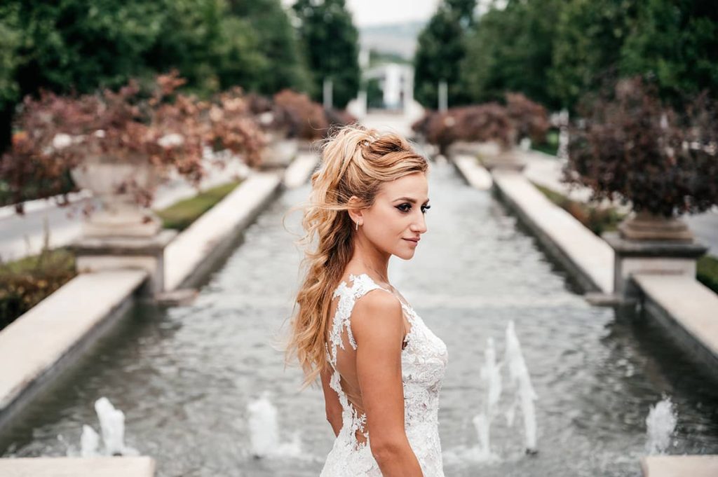 Bride in a white gown posing by a fountain in a picturesque wedding in Rome setting