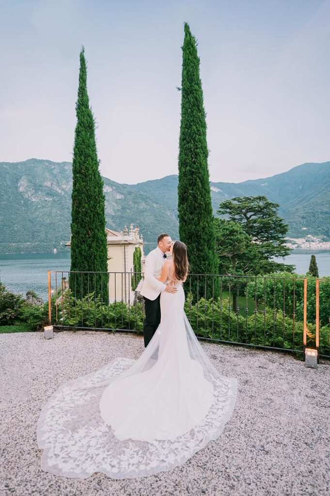 Newlyweds sharing a kiss on a stone terrace overlooking Lake Como, showcasing the intimacy of a Lake Como wedding