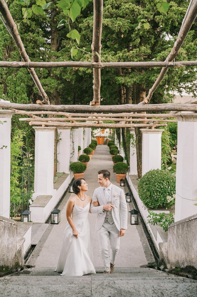 Bride and groom walking under a pergola at Belmond Hotel Caruso wedding Ravello, with lush greenery