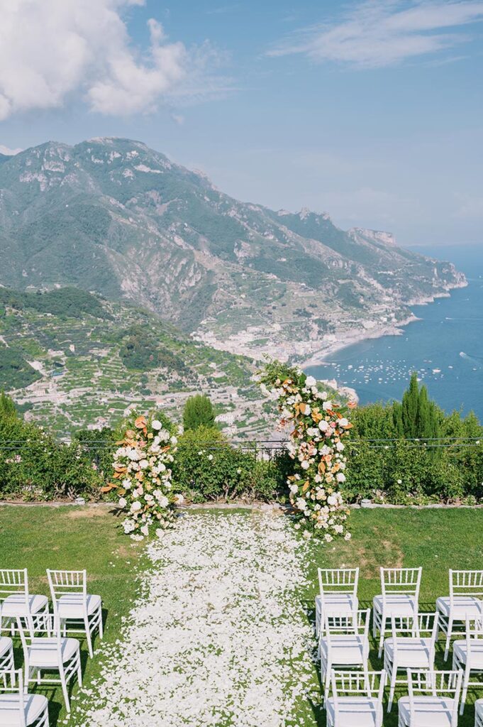 Floral archway overlooking the Amalfi Coast at a Belmond Hotel Caruso wedding Ravello ceremony, with white chairs and petals