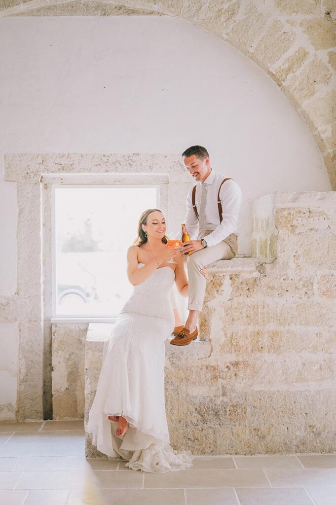 Bride and groom sharing a playful moment inside a stone-walled Apulian venue, shot by a Puglia wedding photographer