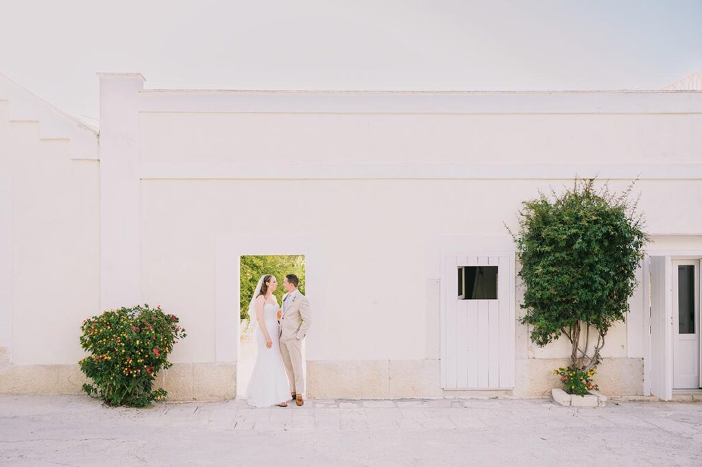 Elegant wedding portrait of a couple framed by a whitewashed wall, styled by a Puglia wedding photographer