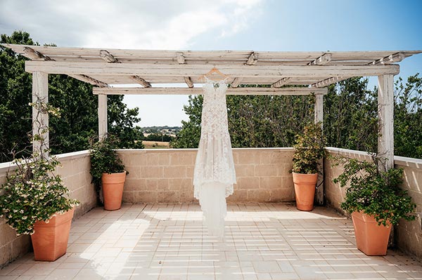 Wedding dress hanging on a pergola in a Mediterranean terrace, styled by a Puglia wedding photographer