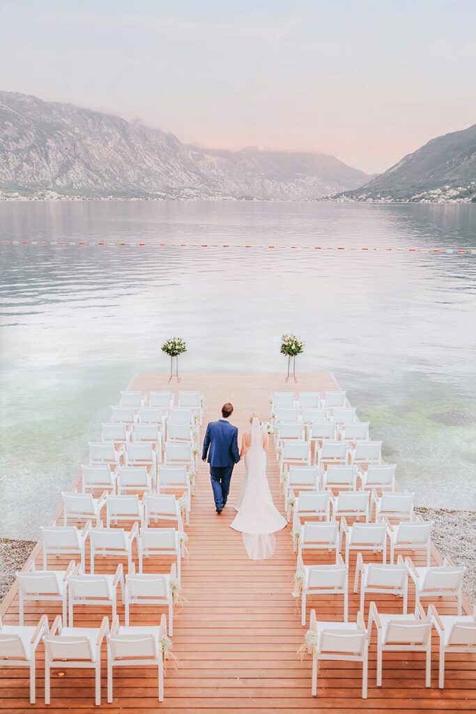 Groom walks a pier toward Lake Como, with ceremony chairs set, a moment captured by a Lake Como wedding photographer