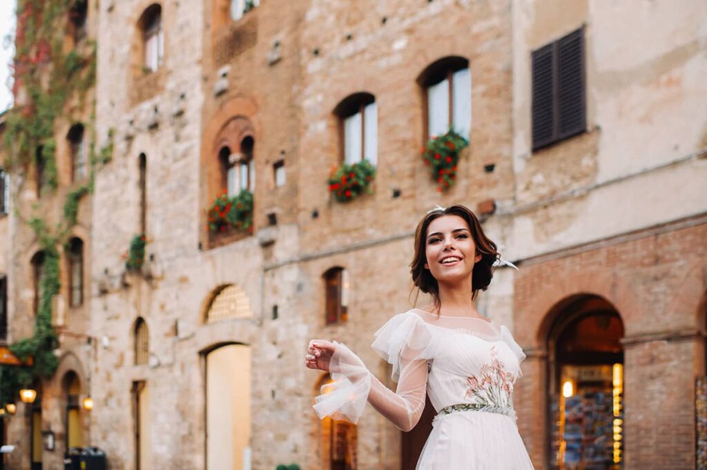 Joyful bride poses against charming Tuscan architecture, a moment captured by your Lucca wedding photographer