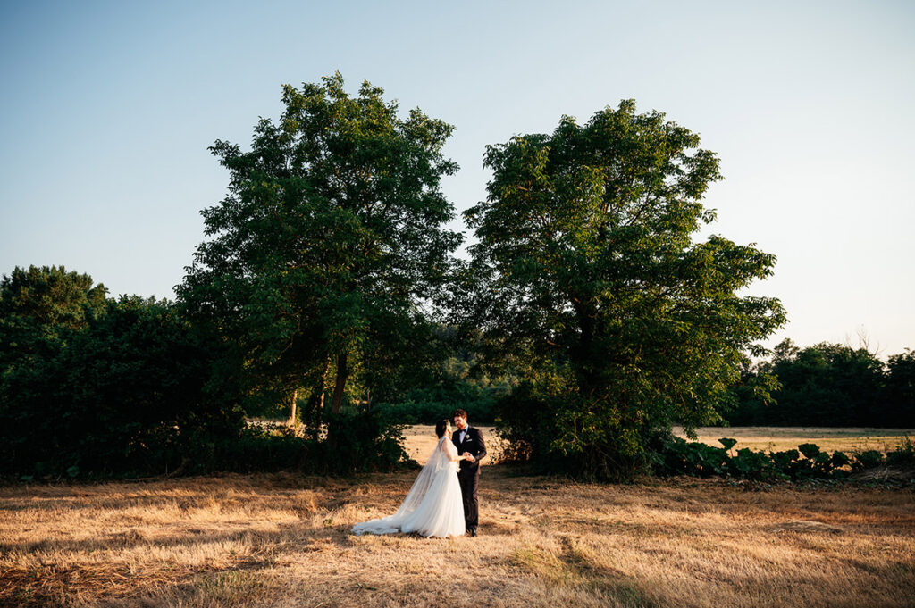 Bride and groom embracing in a picturesque field in Pienza, Tuscany. Pienza wedding photographer capturing a romantic moment