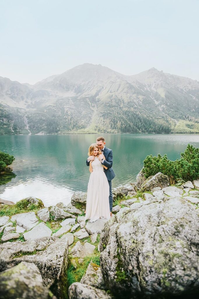 Couple embraces by Lake Como with mountains in the background, a romantic shot by a Lake Como wedding photographer