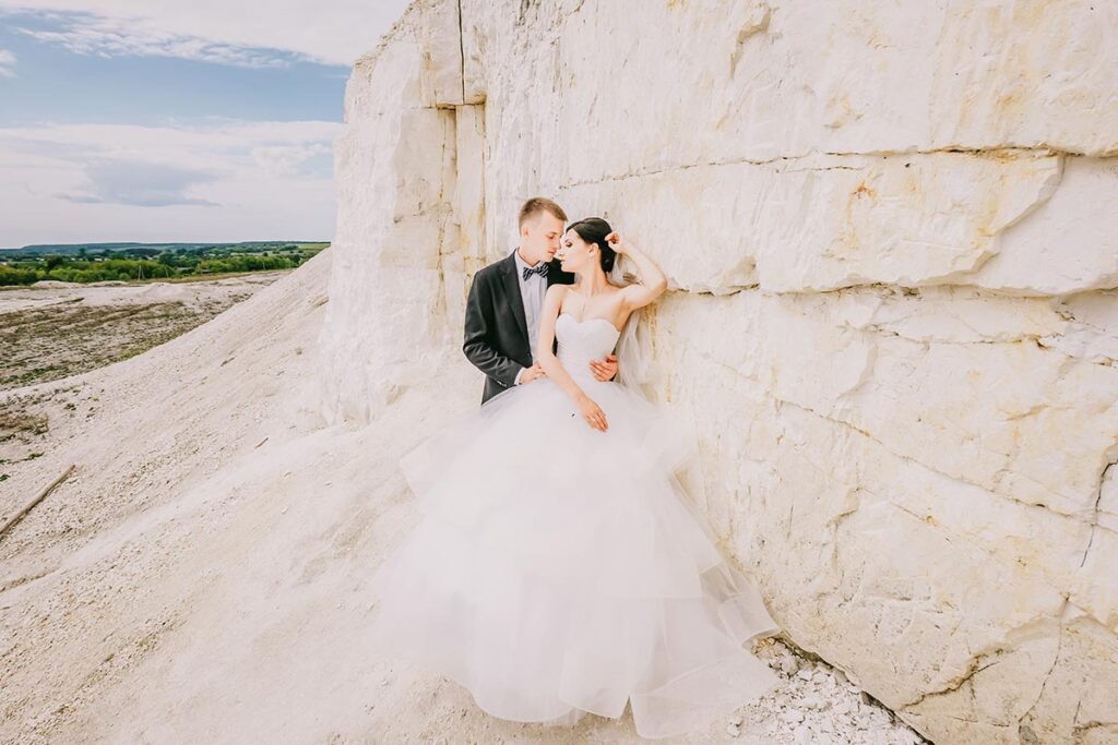 Italian Wedding Photographer captures a couple against a white rock formation in Sicily, highlighting the unique landscape