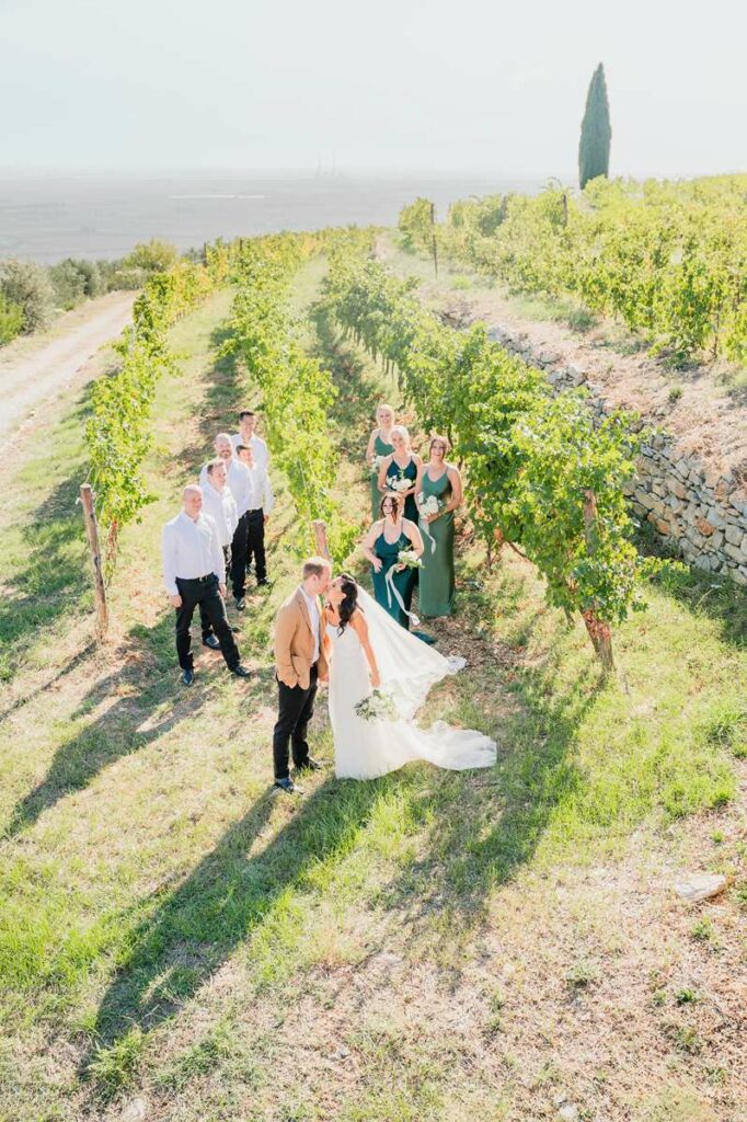 Wedding party walking through vineyard, captured by Florence wedding photographer, showing scenic location