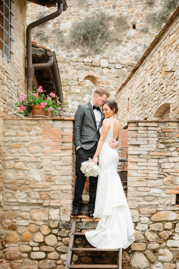 Couple posing on stone steps by a rustic stone wall, captured by Florence wedding photographer, showing architectural detail
