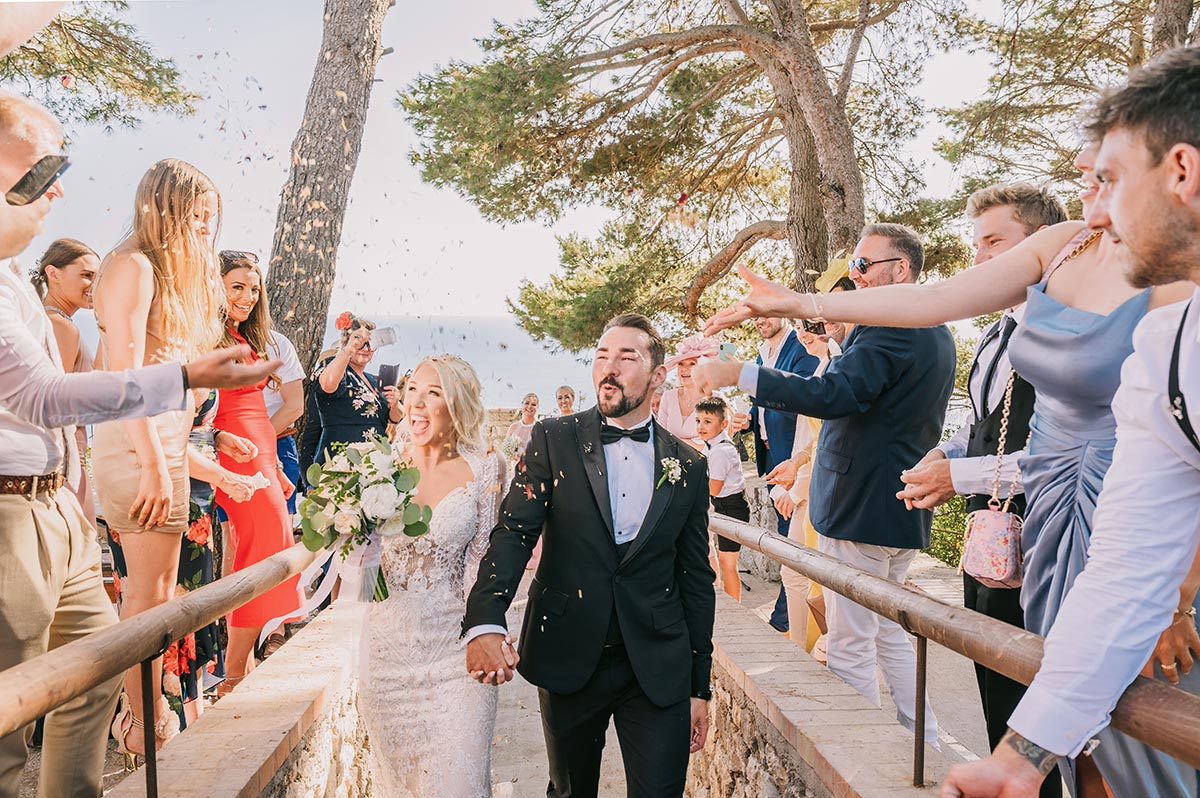 A Capri wedding photographer captures a joyful couple celebrating with guests on a scenic terrace